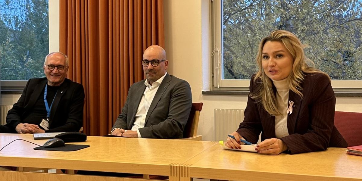 En kvinna och två män sitter vid ett konferensbord.