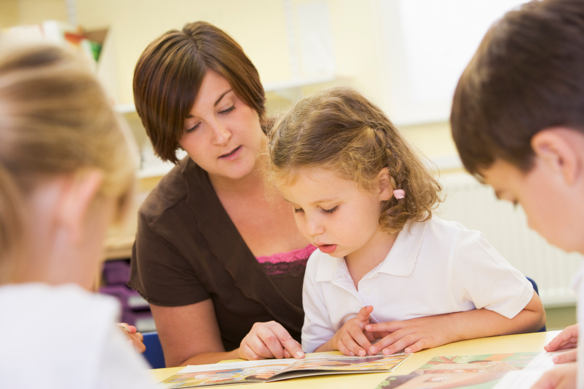 Tre barn som läser tillsammans med en vuxen.