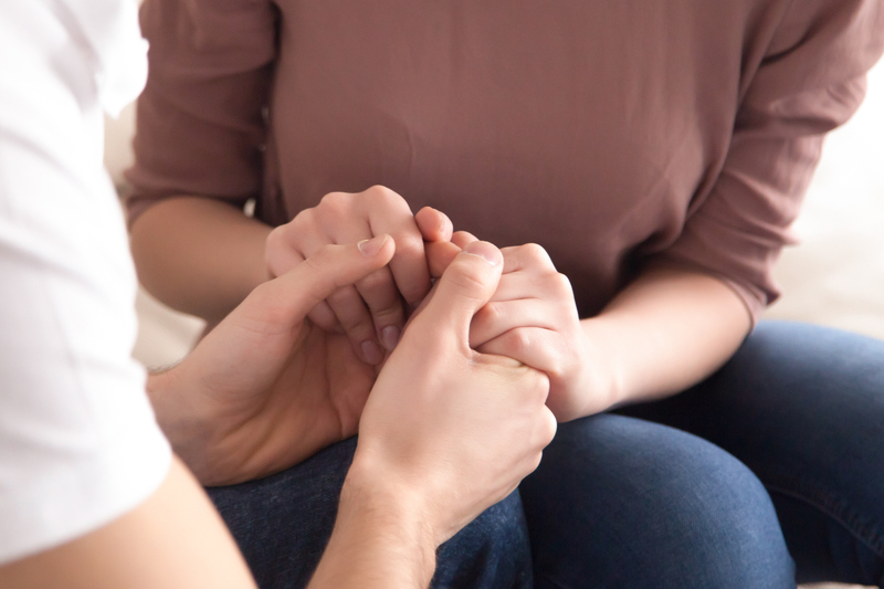 Närbild av två personer som sitter och håller händerna.