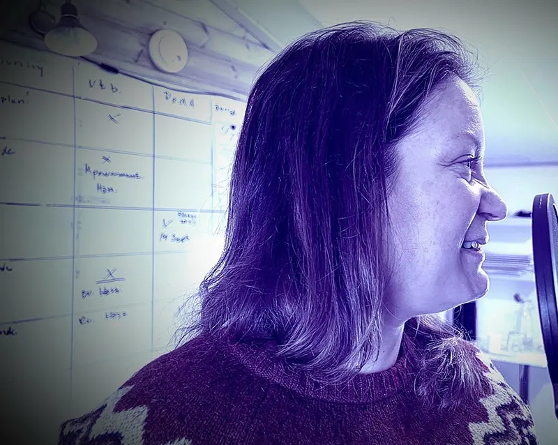 Profilbild på en leende person med axellångt hår och en stickad tröja