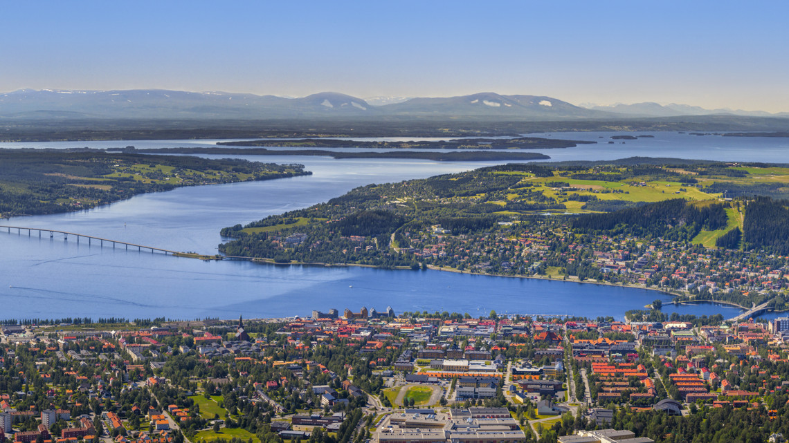 En fabriksarbetare med svetsmask står och svetsar något med glöd sprutandes omkring.