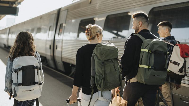 Familj med packning går och pratar  på en tågperrong.