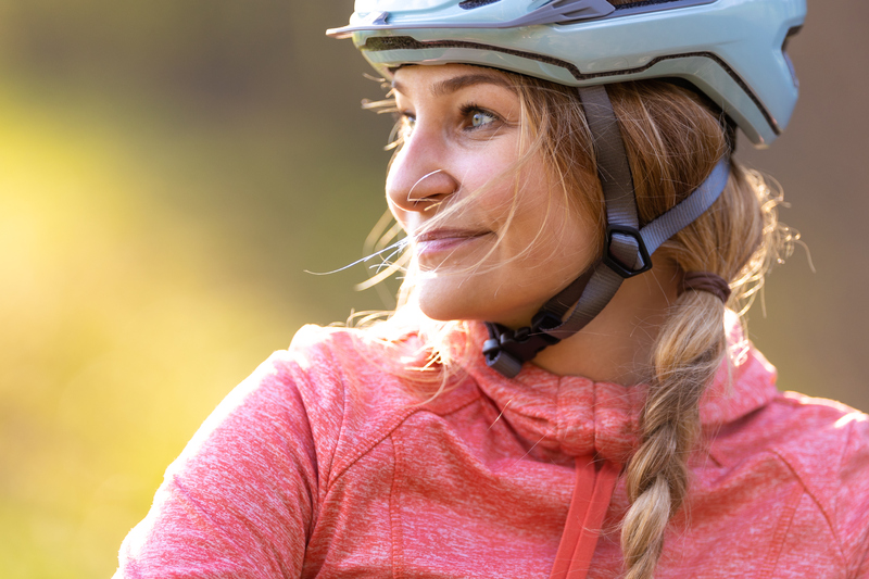 Närbild på en vuxen person i rosa jacka och med cykelhjälm på sig.