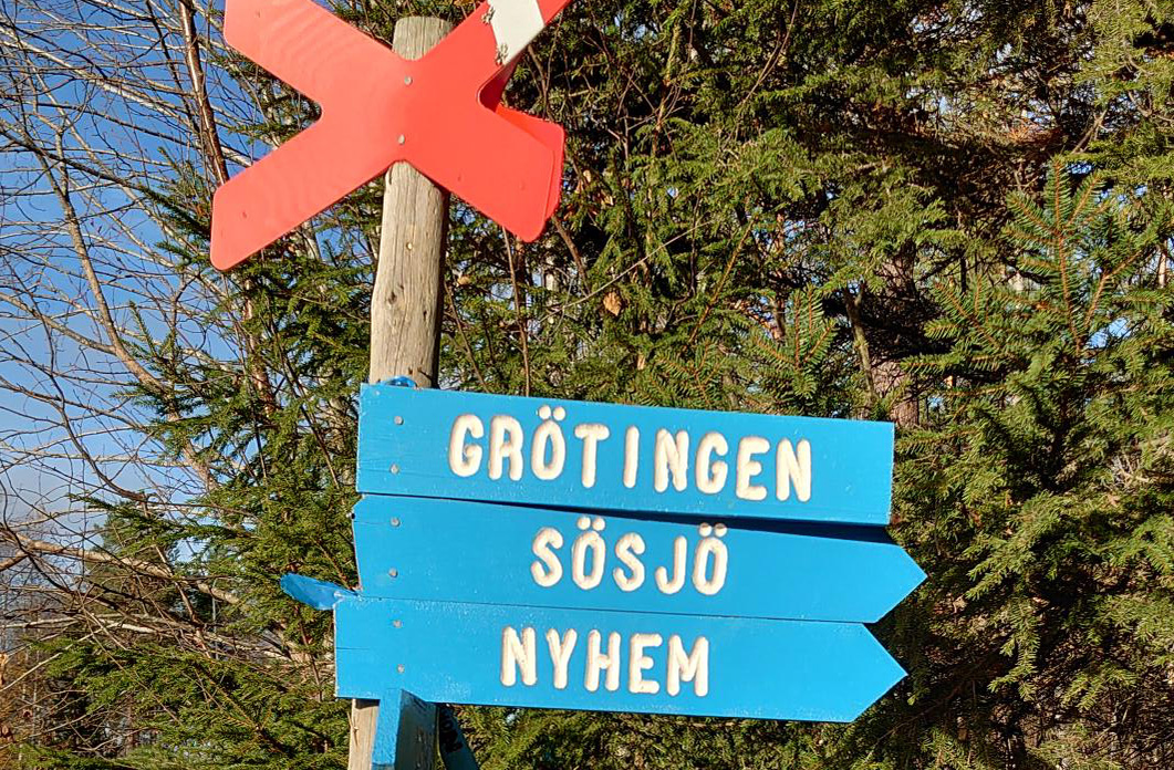 Bild med ett rött ledkryss och tre blåa skyltar med texten Grötingen, Sösjö och Nyhem. 