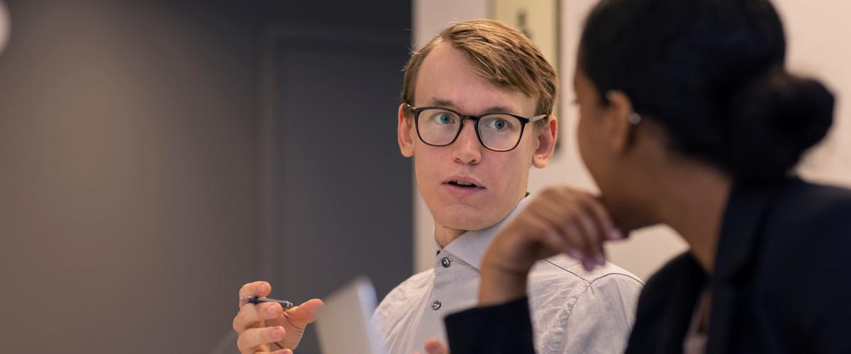 Två personer sitter vid ett bord och pratar med varandra.