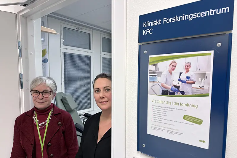 Två personer kikar fram ur en dörröppning och ser glada ut