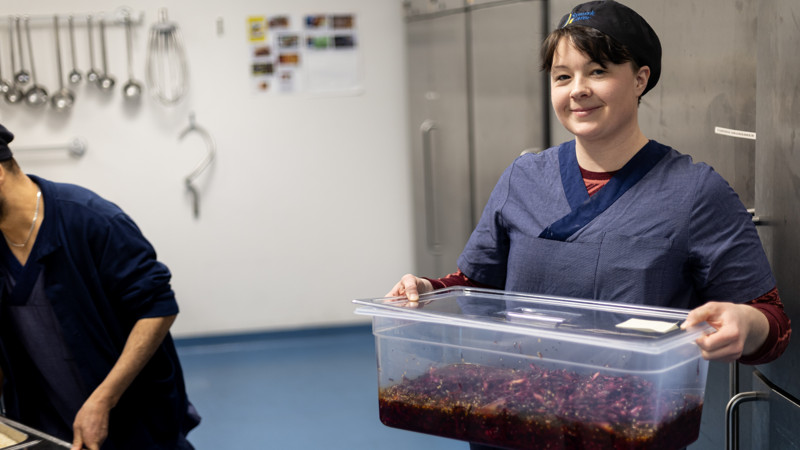 En kvinna håller i en behållare med sallad.