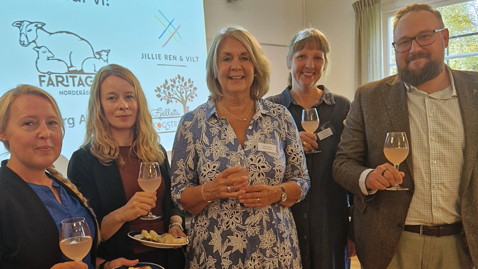 Fem personer står med tallrikar och glas i händerna.