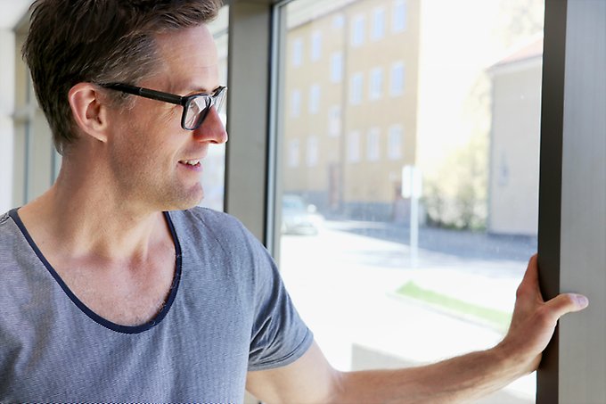 karl-johan lundström står och tittar ut genom ett fönster med vänster arm på fönsterkarmen