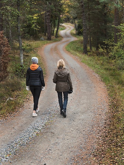 Två kvinnor går på en skogsväg.