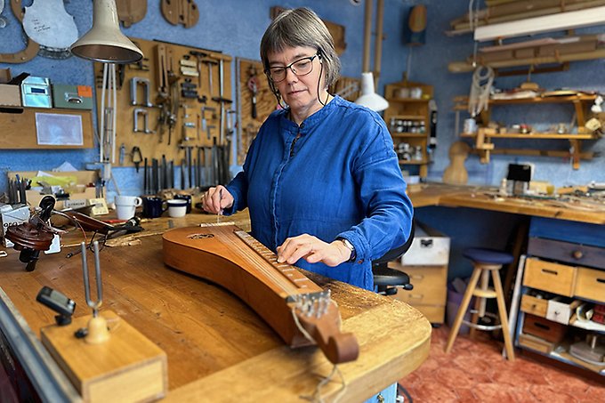 Astrid Pullar står och spelar på det gamla stränginstrumentet Hummel, ett päronformat gammalt harpinstrument.