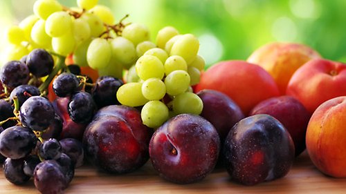 En hög med frukter och grönsaker mot en vit bakgrund.